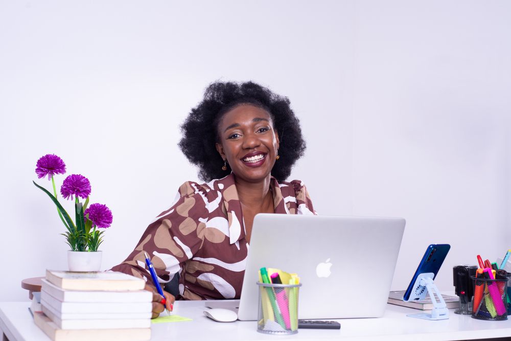 Une jeune professionnelle souriante à son bureau, devant son ordinateur